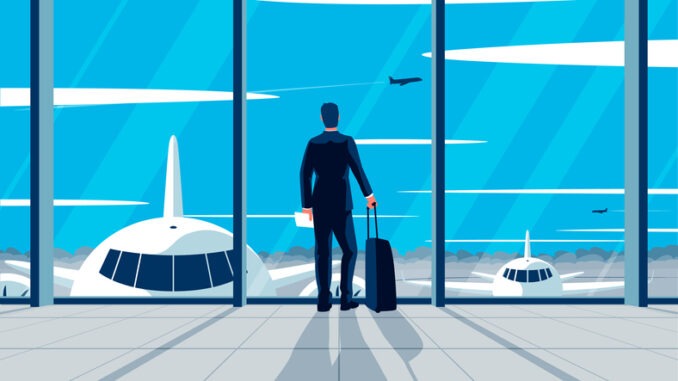 businessman standing in the airport. Concept of a man wearing suit with suitcase standing in the airport lounge looking at the airfield. Departure awaiting hall interior