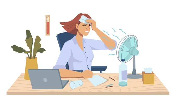 Employee working in office during summer heat, isolated using a fan to try to cool down 