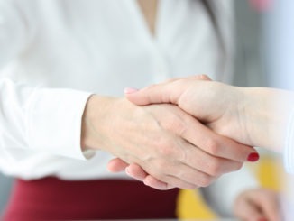 Business women colleagues shaking hands in office closeup