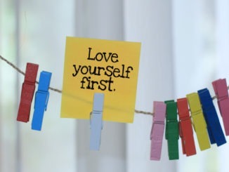 Love yourself first. Positive words for mental health support concept with paper note hanging on rope.