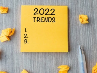 2022 Trends word on yellow note with pen and crumbled paper on wooden table background. New Year New Start, Resolutions, Strategy and Goal concept