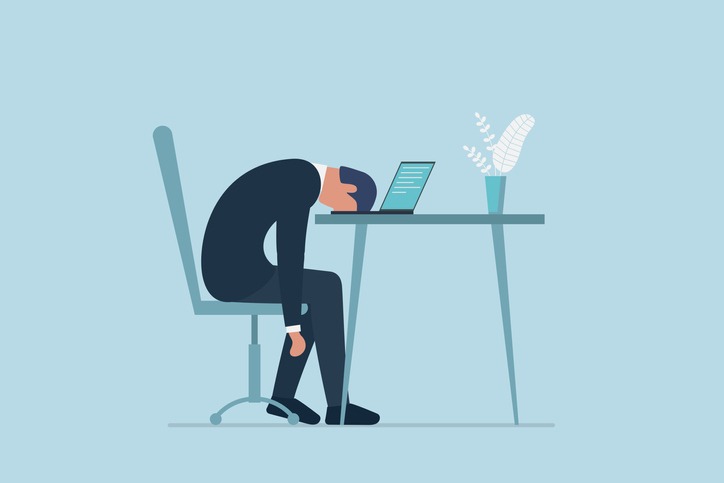 Professional burnout syndrome. Exhausted sick tired male manager in office sad boring sitting with head down on laptop.