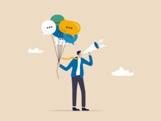 businessman holding speech bubble balloons while talking on megaphone.