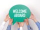 Group of people holding the WELCOME ABOARD written speech bubble