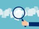 Crop hand of cartoon employer with magnifier looking through documents