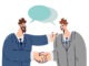 Handshakes of two white collar workers with dialogue clouds entering into partnership agreement